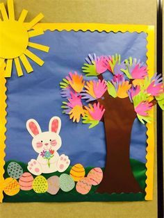 a bulletin board decorated with handprints and an easter tree in the center, surrounded by colorful paper flowers