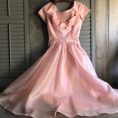 "1950s Pink Taffeta Cocktail Dress, Mid Century Formal Attire, Bridesmaid Dress For the the belle of the ball - wallflowers need not apply. Shimmery and feminine, yet demure and subtle. As you walk across the room you can hear that soft rustle of the taffeta flowing and gliding along with you every step of the way. Peachy/Pink tones, cap sleeve, scoop neckline with a tulip ruffle underneath the bust line and sweet little bow on the left side. Princess seams in front and back, a generous gatherin Vintage Ball Gown Dresses For Vintage Events, Vintage Full Skirt Wedding Dresses, Vintage Dresses With Pleated Bodice For Vintage Events, Vintage Ball Gown With Fitted Bodice, Retro Full Skirt Wedding Dress, Vintage Tea Length Dress With Pleated Bodice, Vintage Dresses With Pleated Bodice And Tea Length, Vintage Dress With Fitted Bodice And Full Skirt, 1950s Style Tea Length Wedding Dress