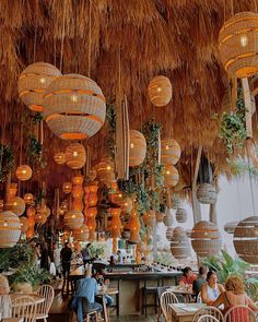 people sitting at tables in a restaurant with lots of lights hanging from the rafters