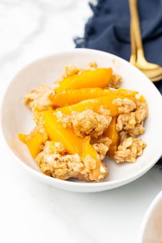 a white bowl filled with oatmeal and peaches on top of a table