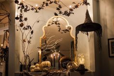 a decorated mantle with candles, pumpkins and other decorative items on it in front of a mirror