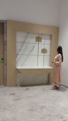 a woman standing in an empty room looking at a window with leaves painted on it