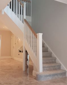 a staircase leading up to the second floor in a home with marble floors and white railings