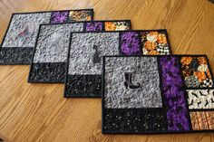 four quilted coasters sitting on top of a wooden table