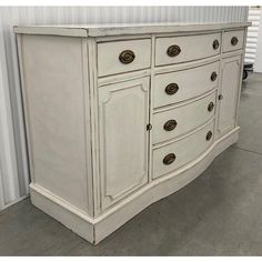 an old white dresser with many drawers and knobs on the doors is sitting in front of a wall