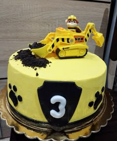 a yellow cake with black and white frosting has a construction vehicle on top that says 3