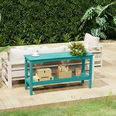 a blue table sitting on top of a wooden floor next to a lush green bush