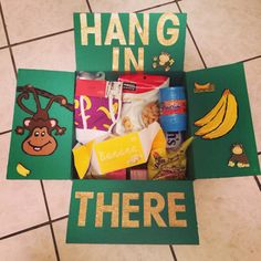 a box filled with snacks sitting on top of a tiled floor next to a sign that says hang in there