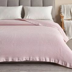 a bed with white pillows and pink bedspread