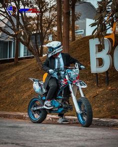 a man riding on the back of a motorcycle down a street next to a sign