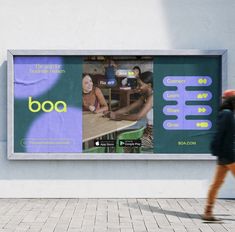 a person walking past a billboard on the side of a building with people sitting at tables