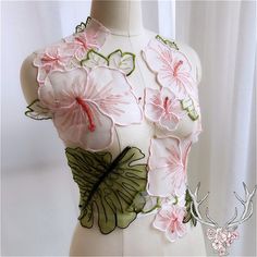 a mannequin with pink flowers and green leaves on it's chest, in front of a white curtain