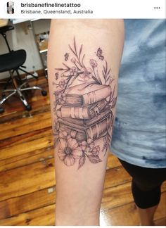 a tattoo with books and flowers on it