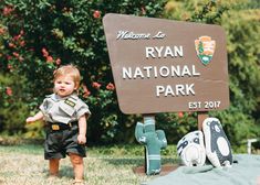 a little boy standing next to a sign for ryan national park