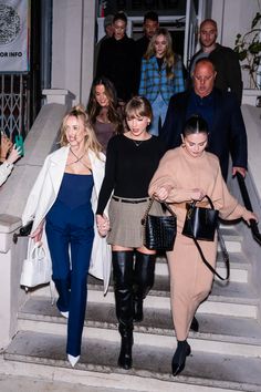 two women are walking down the stairs with their purses in hand and one woman is wearing