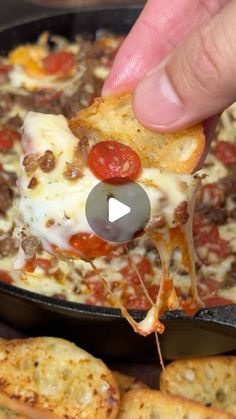 someone is taking a piece of pizza from a skillet with cheese and tomatoes on it