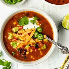 two bowls of mexican soup with tortilla chips and sour cream on the side