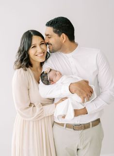 a man and woman holding a baby in their arms