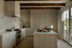 a large kitchen with white cabinets and wooden beams on the ceiling is filled with fruit