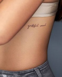 a woman's stomach with the words grateful soul tattooed on her lower back side