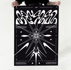 a man holding up a black and white poster with an abstract design in the middle