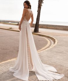 a woman in a white wedding dress standing on the street with her back to the camera