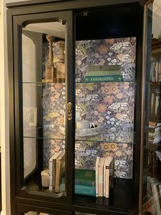 a book case with books and other items in it's glass front display cabinet