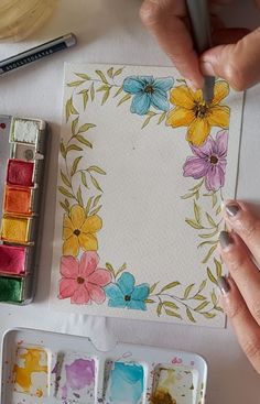 someone is painting flowers on paper with watercolors