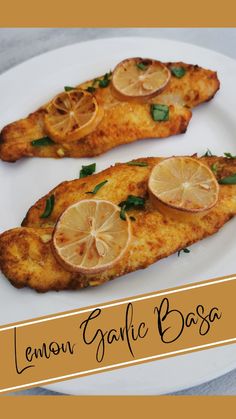 two fish fillets on a white plate with lemon garnish