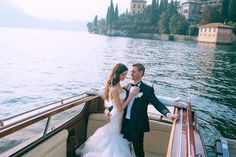 a bride and groom standing on the back of a boat