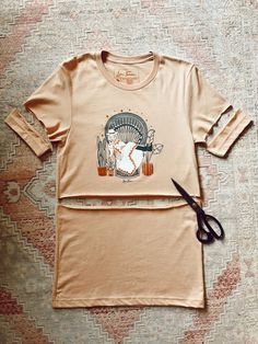 a pair of scissors laying on top of a t - shirt with an image of a woman