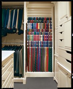 an organized closet with ties hanging on the door and drawers in it, along with white cabinets