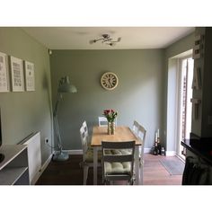 a dining room table with chairs and a clock on the wall