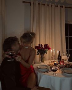 a man and woman sitting at a table in front of a window with candles on it