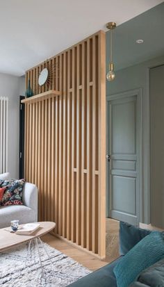 a living room filled with furniture next to a wall covered in wooden slatting