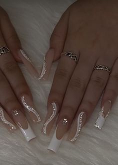 two hands with white and silver nail designs on them