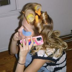 a young woman is talking on her cell phone while holding up some fake hair clips