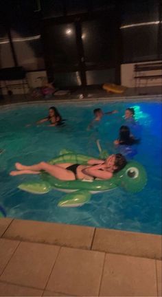 people are swimming in the pool at night with an inflatable turtle floater