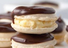 chocolate covered donuts stacked on top of each other with more donuts in the background