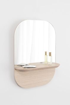 an oval mirror on the wall above a shelf