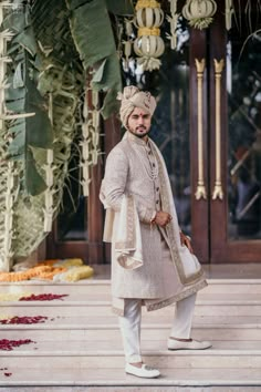 a man in a turban standing on steps with flowers and decorations around him