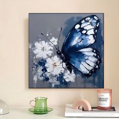 a blue and white butterfly sitting on top of a table next to a green vase