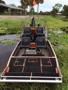 a small boat with four seats on the front is parked in some grass and water