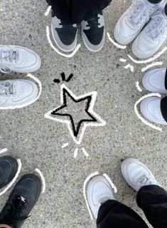 several people standing in a circle with their feet on the ground and one has a star drawn on it