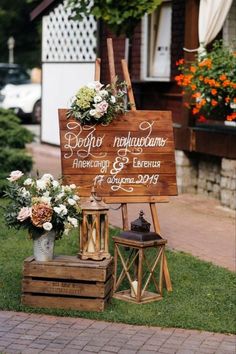 a wooden sign sitting on top of a grass covered field next to flowers and potted plants