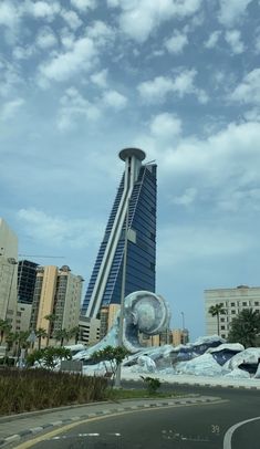 a very tall building sitting next to a road with buildings in the backround