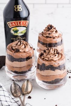 two glasses filled with chocolate dessert next to a bottle of bailey's irish cream