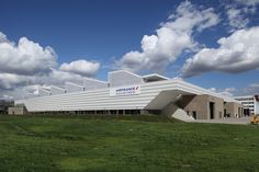 a large white building sitting on top of a lush green field