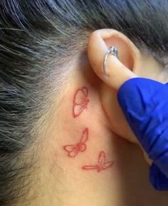 a person with a butterfly tattoo on their left ear and behind the ear is a blue glove