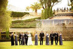 a group of people standing on top of a lush green field next to a fountain